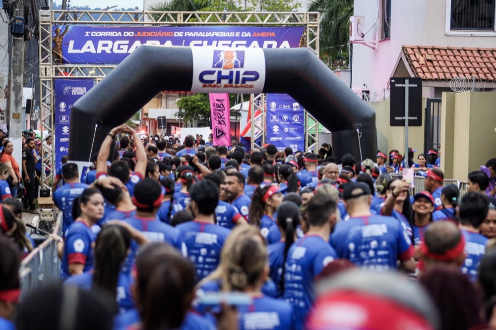 Multidão de atletas cruzando o arco de largada da 1ª Corrida do Judiciário