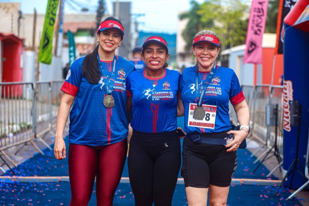 Atletas celebrando juntas no tapete azul da chegada